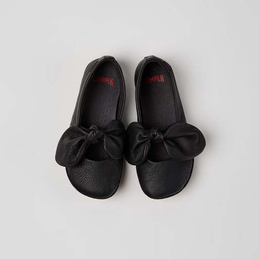 Pair of black shoes with bows on a light gray background