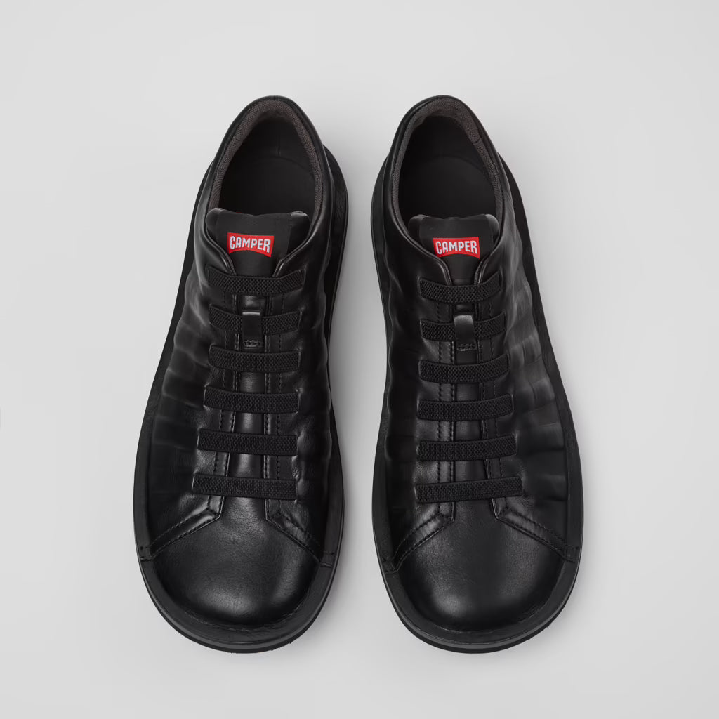 Pair of black sneakers with a brand logo on a light gray background