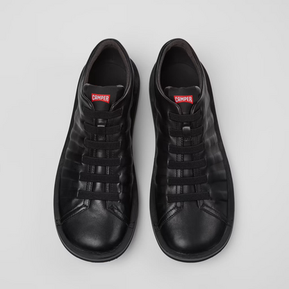 Pair of black sneakers with a brand logo on a light gray background