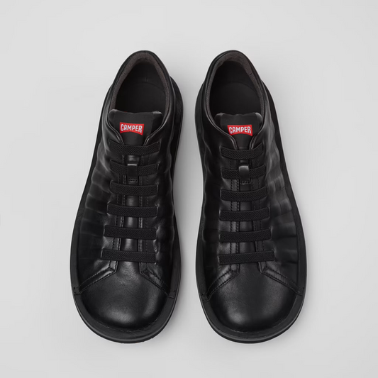 Pair of black sneakers with a brand logo on a light gray background