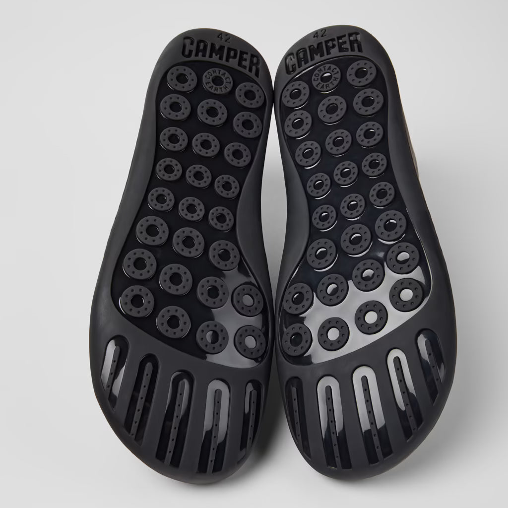 Black sole shoes with unique tread pattern on a light gray background