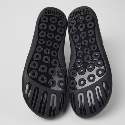Black sole shoes with unique tread pattern on a light gray background