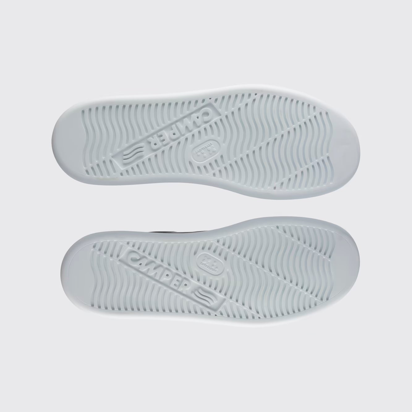 Gray sneaker soles with brand logo on a light gray background