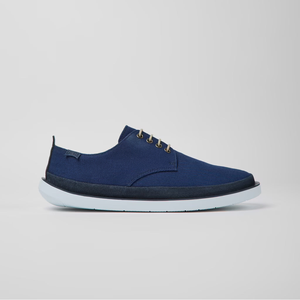 Blue slip-on shoe with white sole on a light gray background