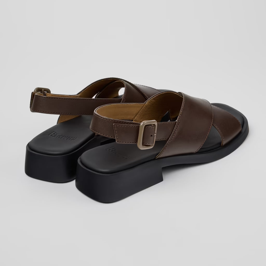 Brown sandals with black soles on a light gray background