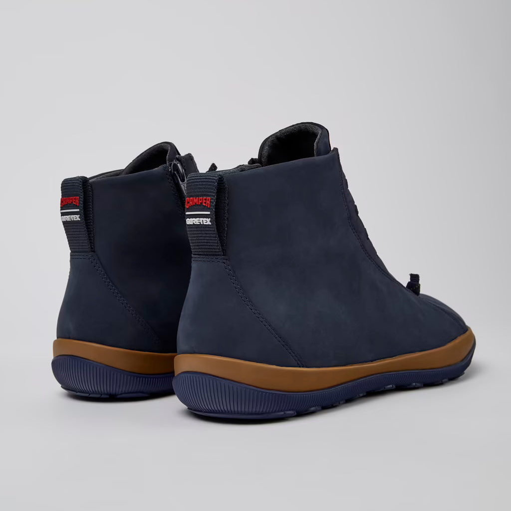 Pair of navy blue ankle boots with brown soles on a light gray background