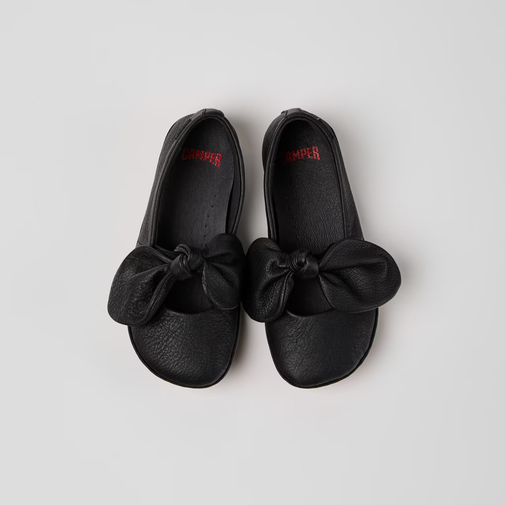 Pair of black shoes with bows on a light gray background