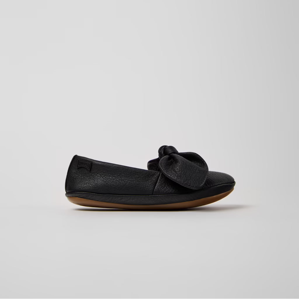 Black flat shoe with a bow on a light gray background