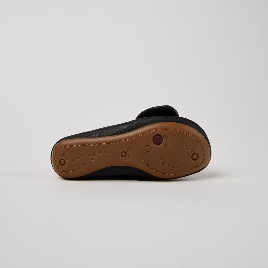 Single sandal with brown sole and black upper on a light gray background