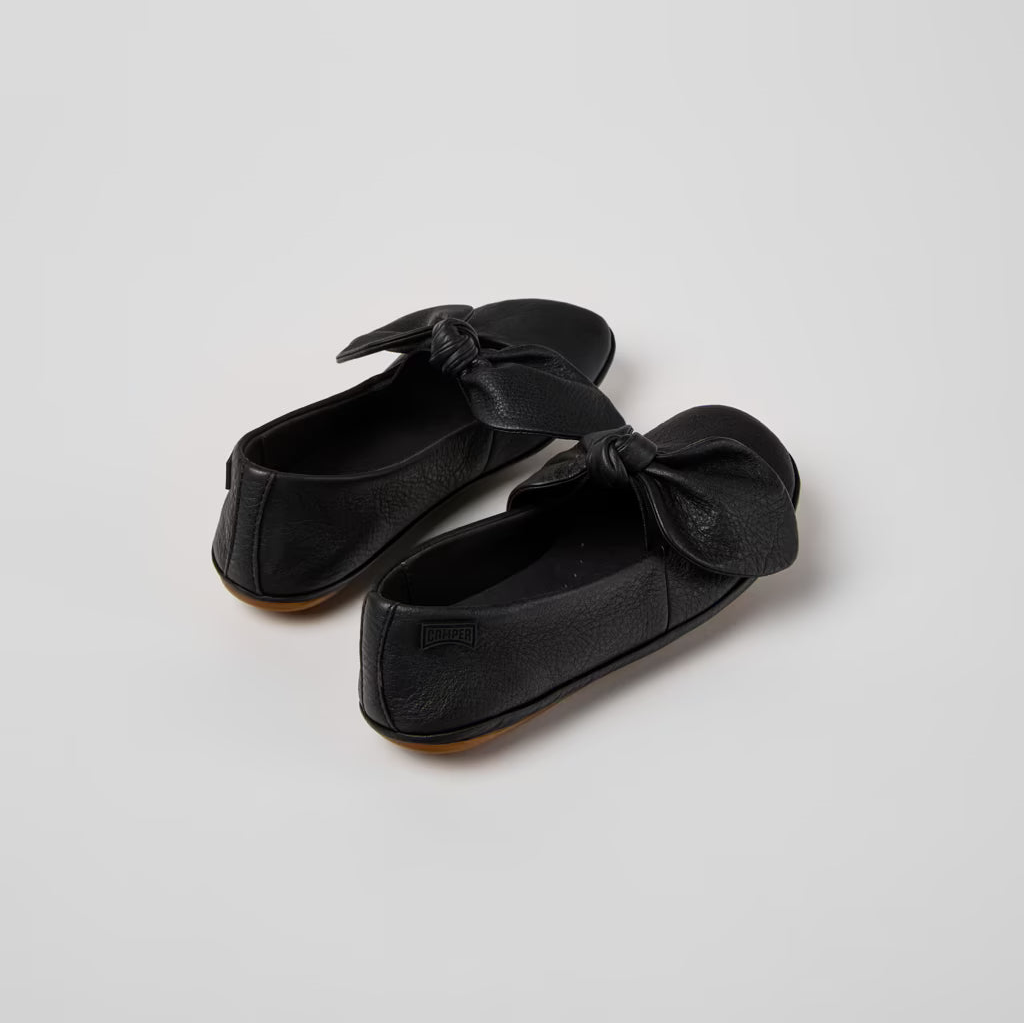 Pair of black loafers with bow details on a light gray background