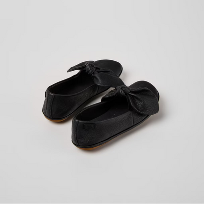 Pair of black loafers with bow details on a light gray background